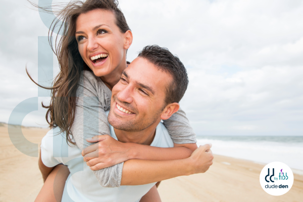 man and woman having fun on beach smiling